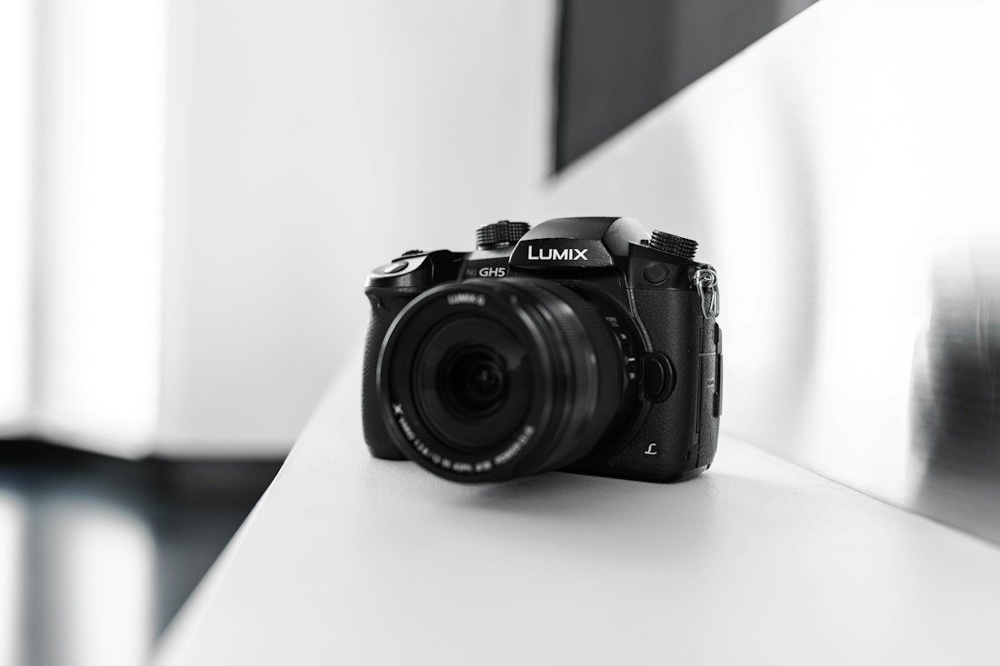 Appareil photo hybride Panasonic Lumix posé sur un plan de travail blanc
